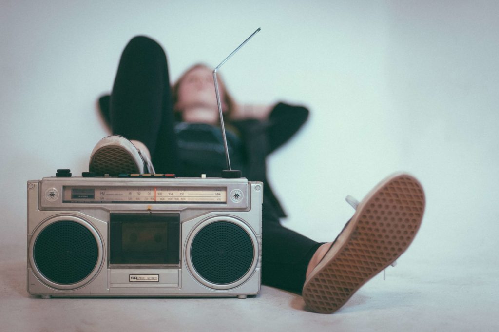 Person listening to the radio. Radio broadcasts reports played songs to PROs, so performers and publishers earn performance royalties.